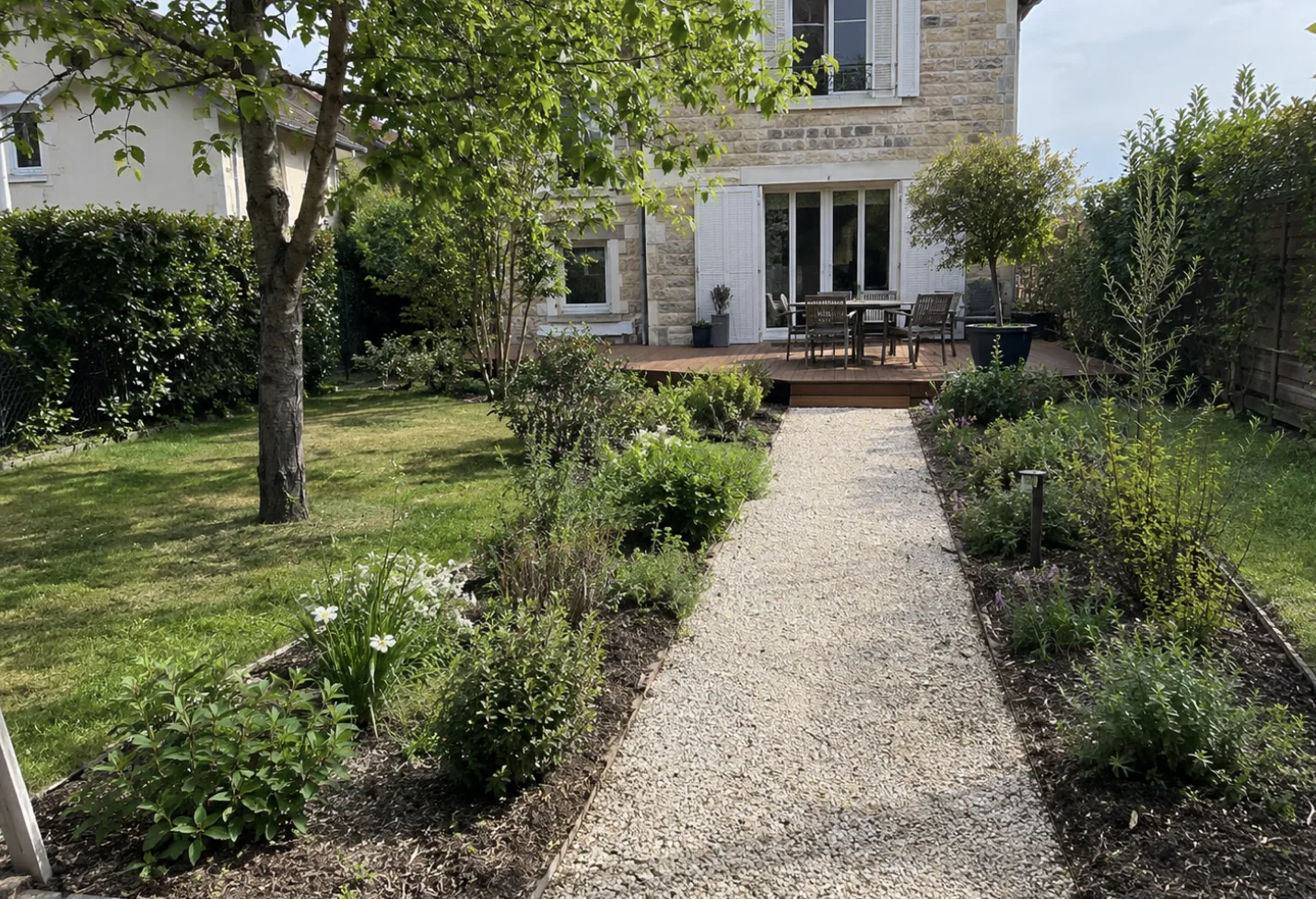 Allée en gravier menant à une terrasse en bois dans un jardin à Chatou